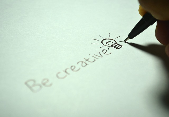 Handschriftlich geschriebener Schriftzug "be creative" mit einem Glühbirnen-Symbol